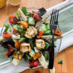 Roasted Greek Salad served on a glass plate with a black fork.