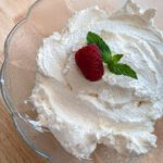 mascarpone whipped cream garnished with a raspberry and mint leaves