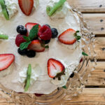 meringue cake topped with fruit and mascarpone whipped cream.