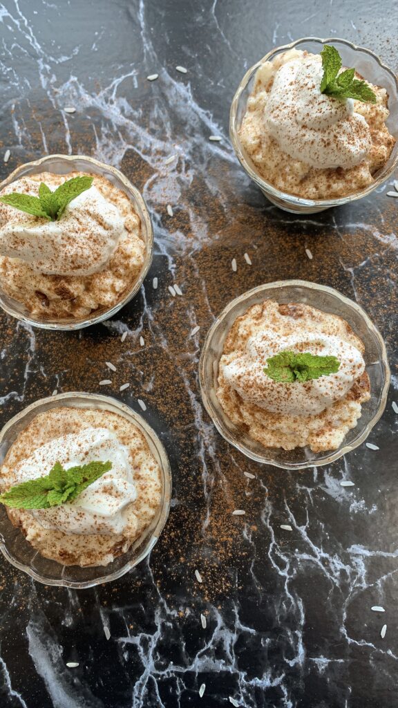 rice pudding topped with homemade whipped cream and garnished with a sprig of mint